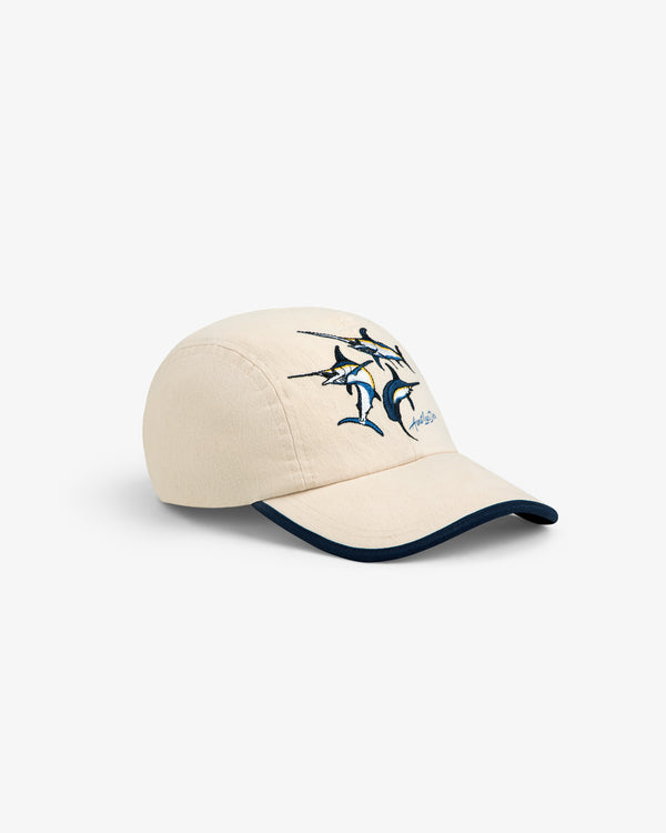 Souvenir Fishing Hat: Beige cap with embroidered blue marlin, dolphins, signature front, and dark blue brim trim.