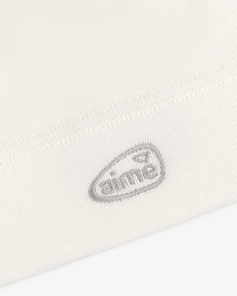 Close-up of the ALD Golf Skull Cap's white knit fabric with a small gray aimé logo embroidered near the hem.