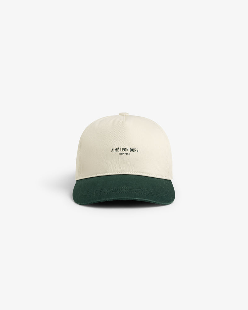 Micro Logo Hat in cream with a dark green brim and AIMÉ LEON DORE NEW YORK text on front, shown on white background.