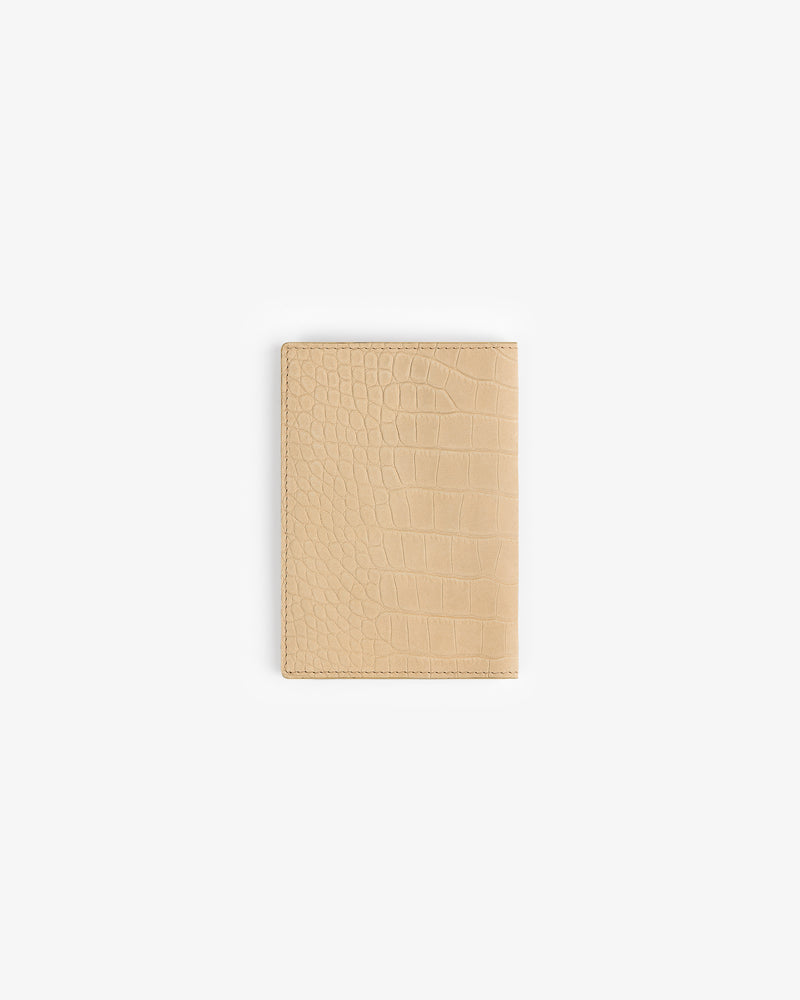 A Croc-Embossed Nubuck Passport Holder in beige leather, displayed on a plain white background.
