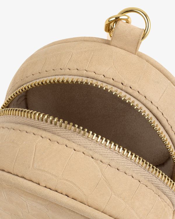 Close-up of the Croc-Embossed Nubuck Keychain Pouch in beige, with two gold zippers and a gold pull tab ring.