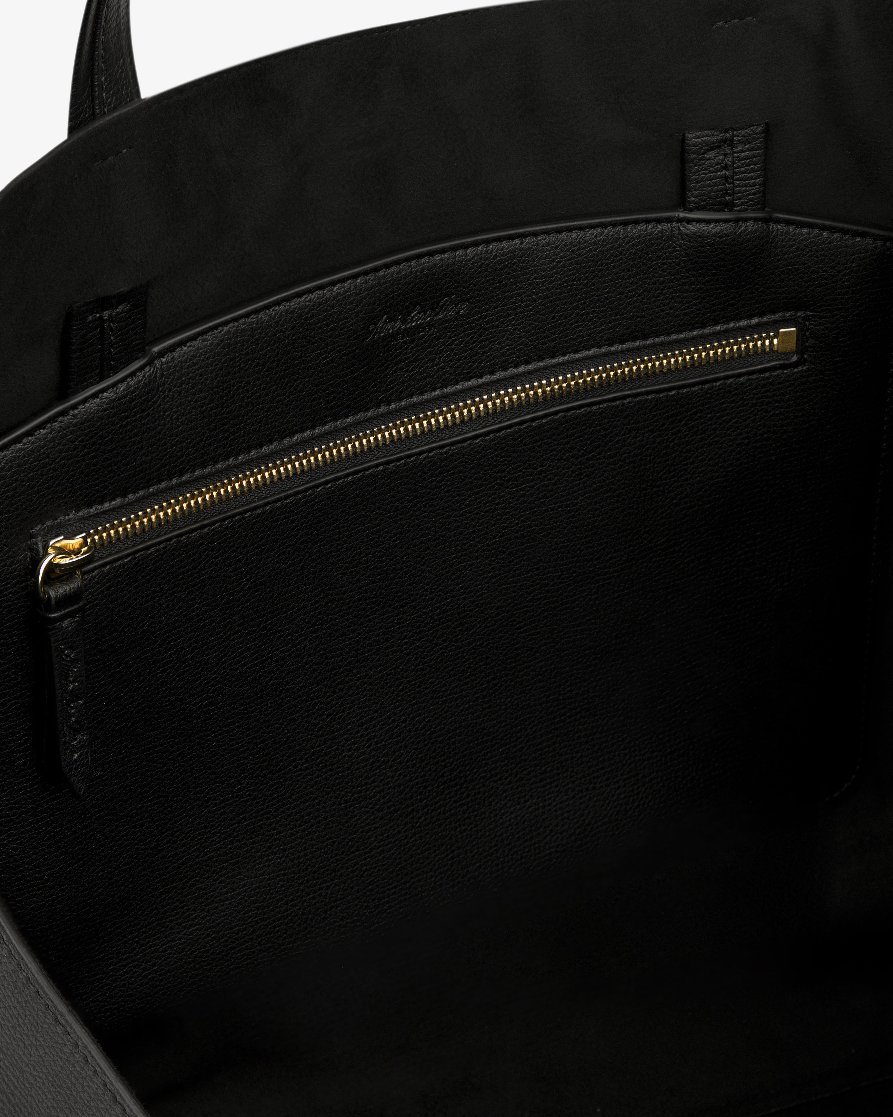 Close-up of the Full Grain Leather Tote Bag's black leather interior with gold zipper pocket and suede lining.