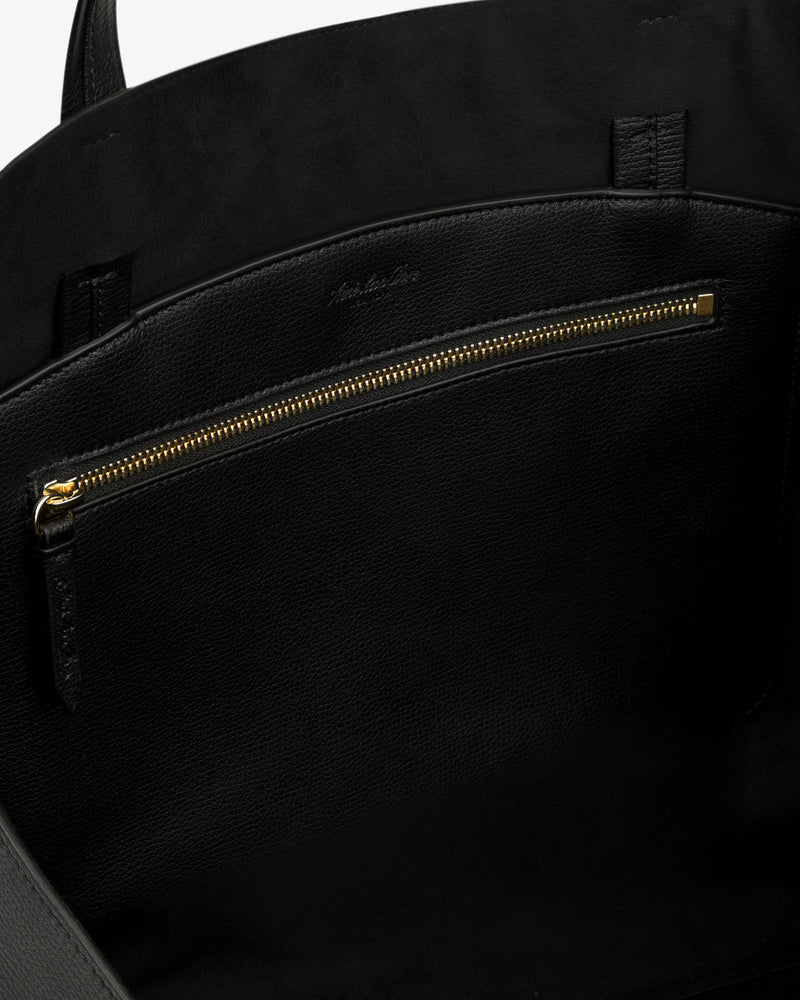 Close-up of the Full Grain Leather Tote Bag's black leather interior with gold zipper pocket and suede lining.
