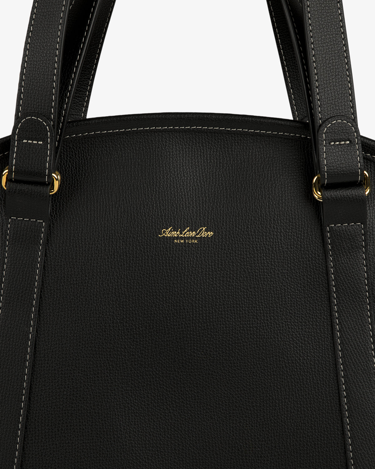 Close-up of the Full Grain Leather Weekender Bag, black with white stitching, gold hardware, and a central gold logo.