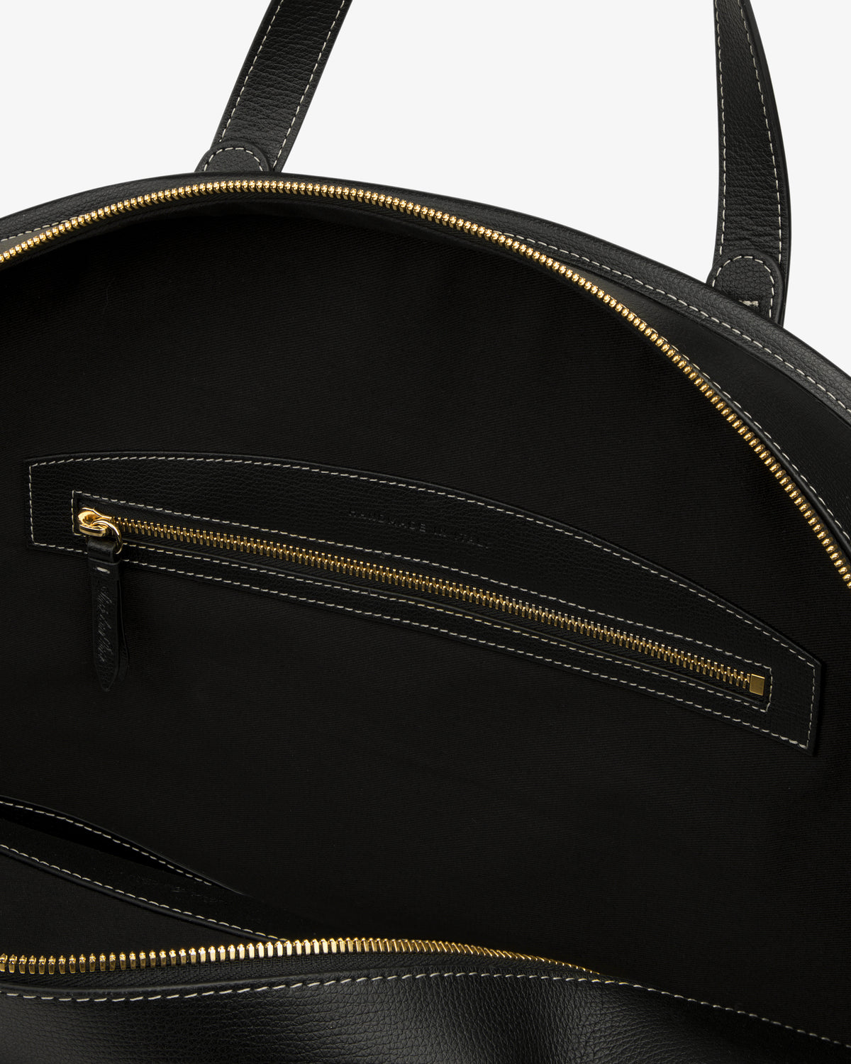 Close-up of the Full Grain Leather Weekender Bag’s black interior with a zippered pocket, gold hardware, and black stitching.