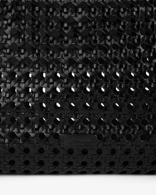 Close-up of the Woven Leather Tote Bag's black, interlaced texture with a small embossed label.