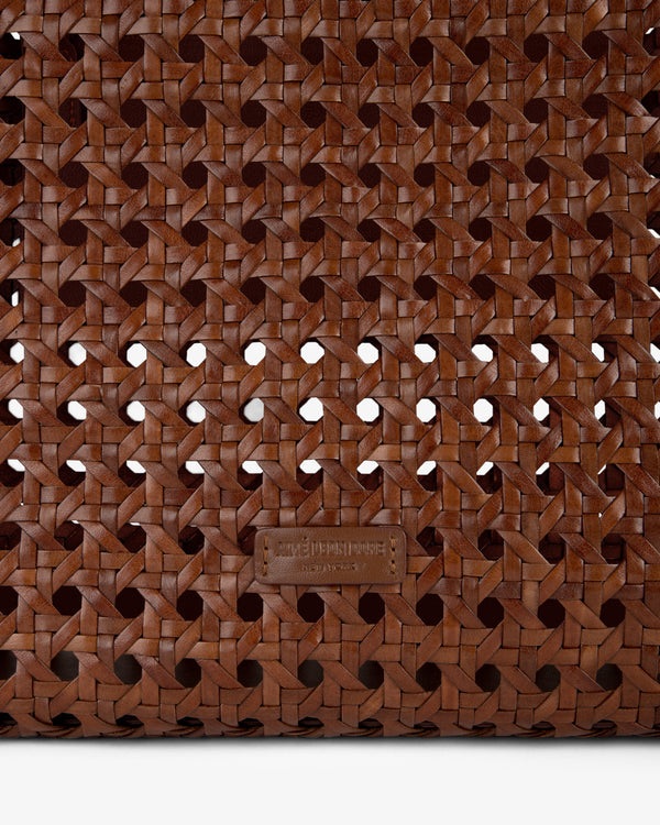 Close-up of the Woven Leather Tote Bag, featuring brown woven leather and a small rectangular label at the bottom center.