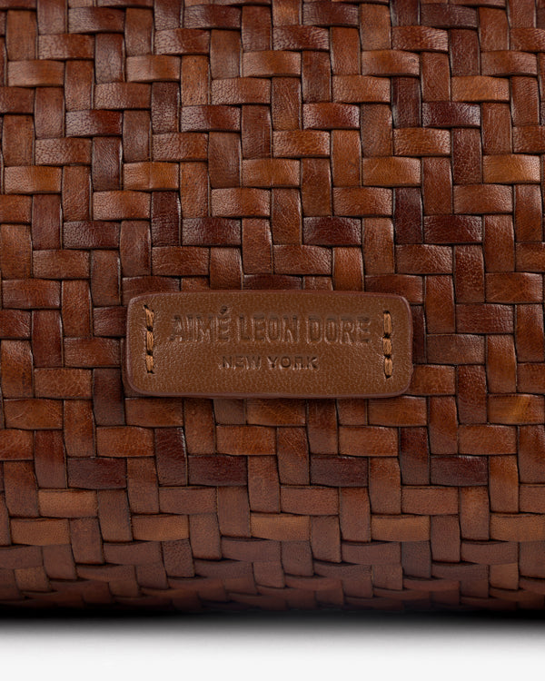 Close-up of the Woven Leather Shoulder Bag’s brown weave and stitched AIMÉ LEON DORE NEW YORK label.
