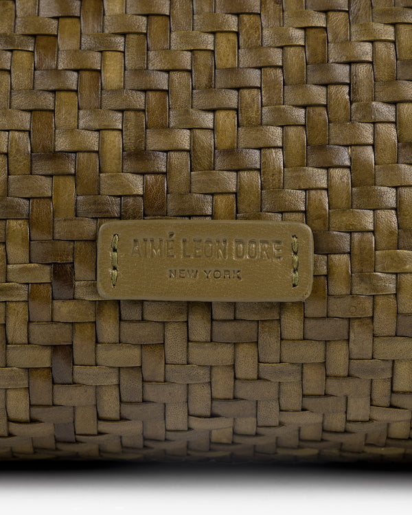 Close-up of a Woven Leather Shoulder Bag with an Aimé Leon Dore New York label stitched at the center.