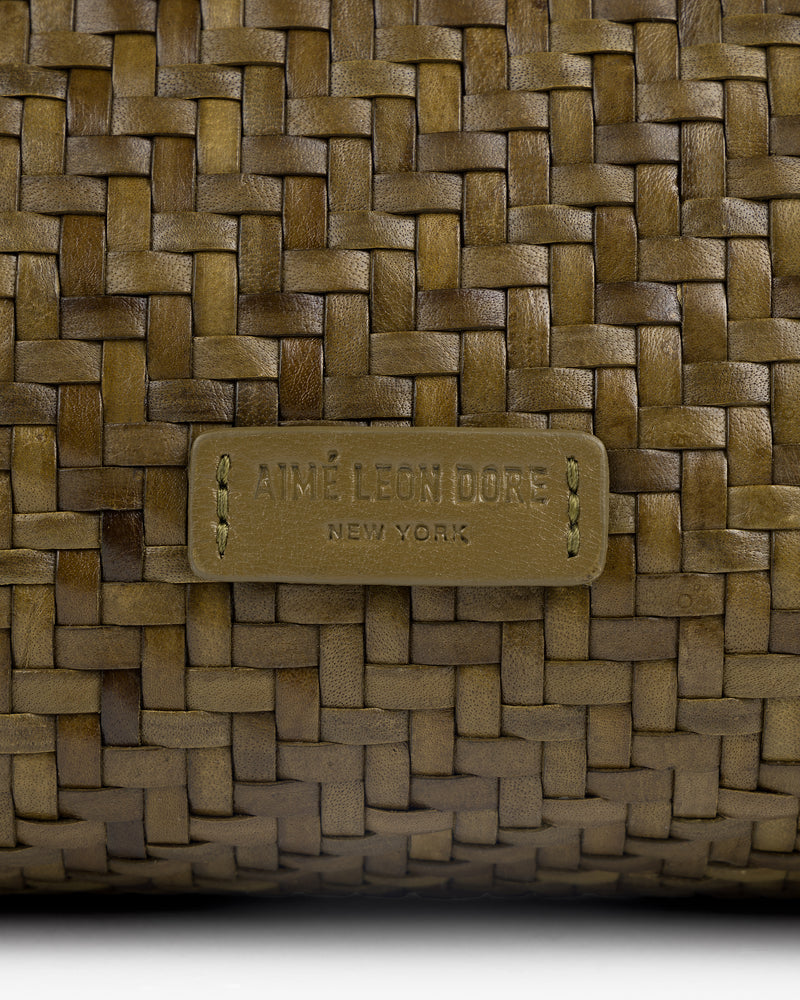 Close-up of a Woven Leather Shoulder Bag with an Aimé Leon Dore New York label stitched at the center.