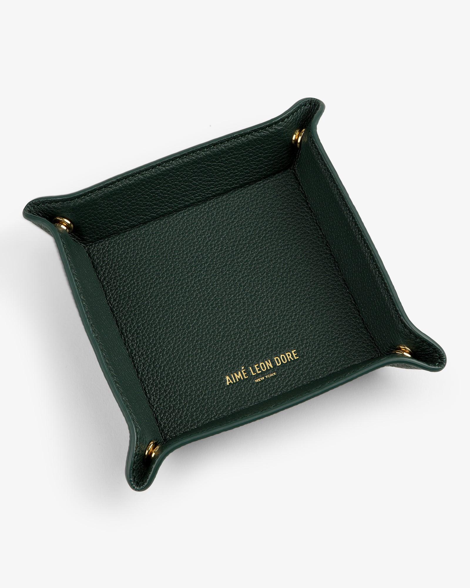 A dark green Leather Catchall with gold corner snaps and AIMÉ LEON DORE embossed in gold inside.