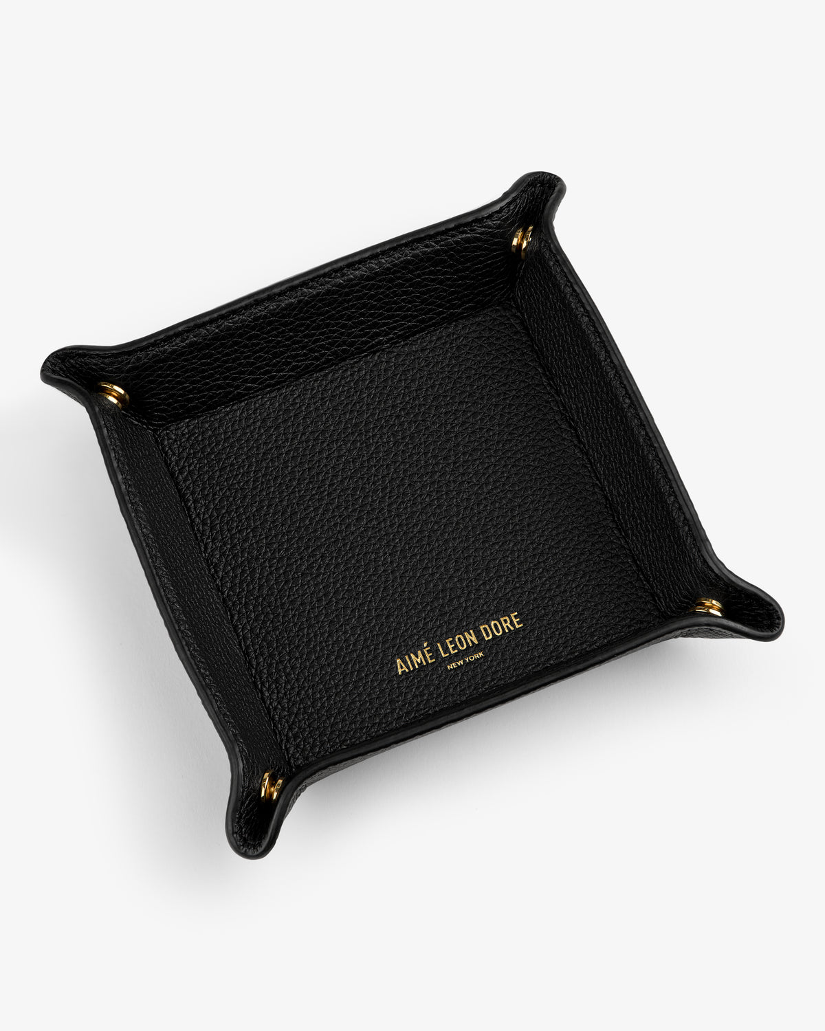 Black Leather Catchall with gold AIMÉ LEON DORE text inside and gold snap buttons at each corner on white background.