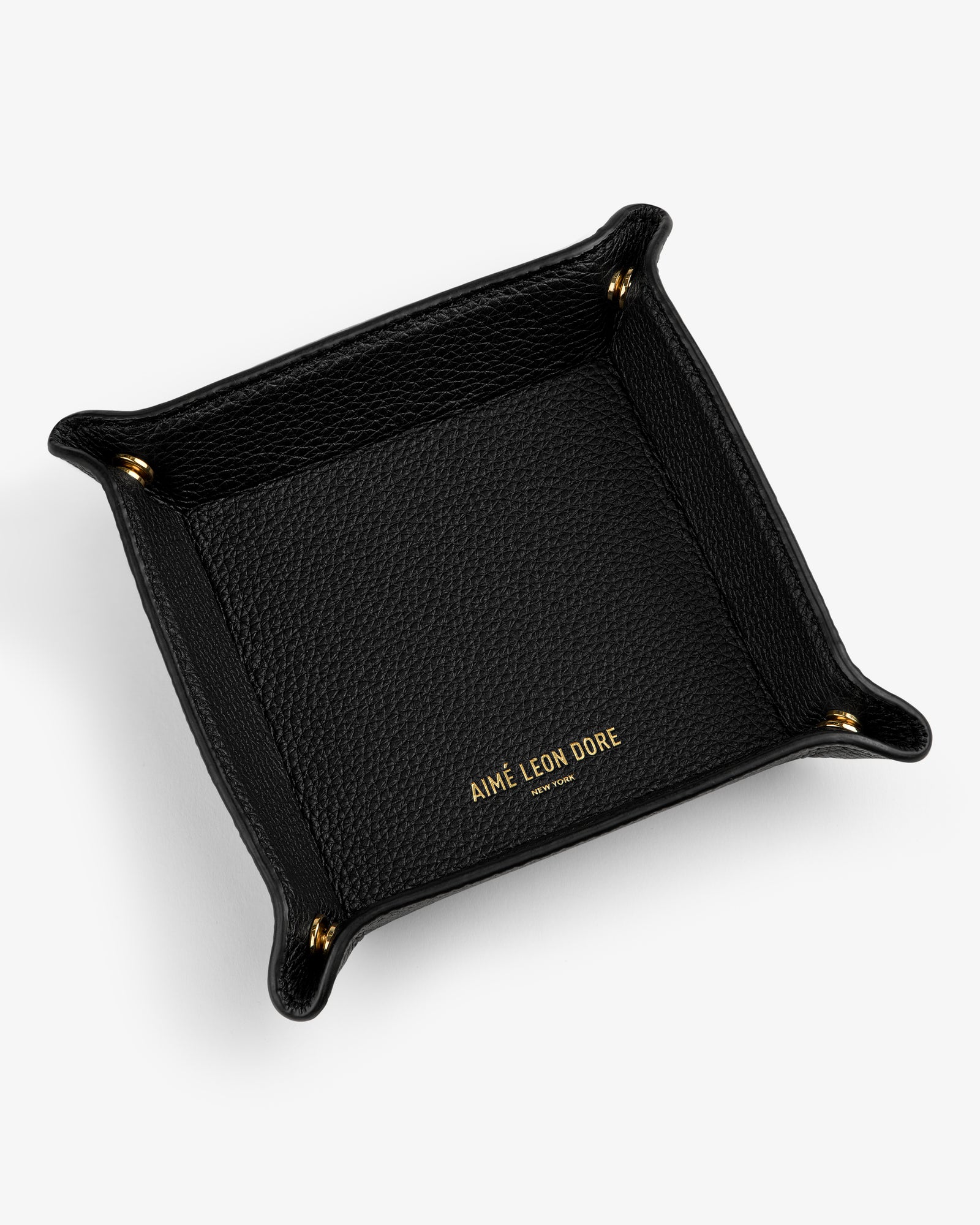 Black Leather Catchall with gold AIMÉ LEON DORE text inside and gold snap buttons at each corner on white background.