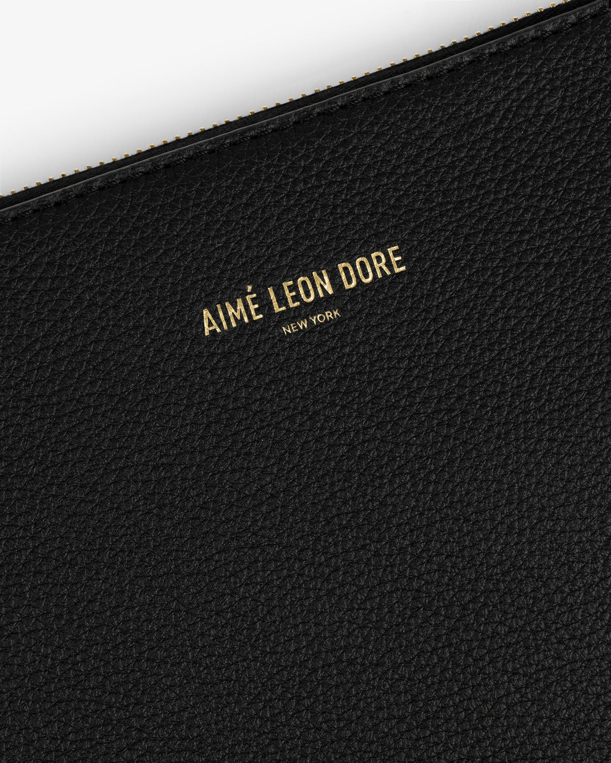 Close-up of a black textured Large Leather Pouch with AIMÉ LEON DORE NEW YORK embossed in gold letters.