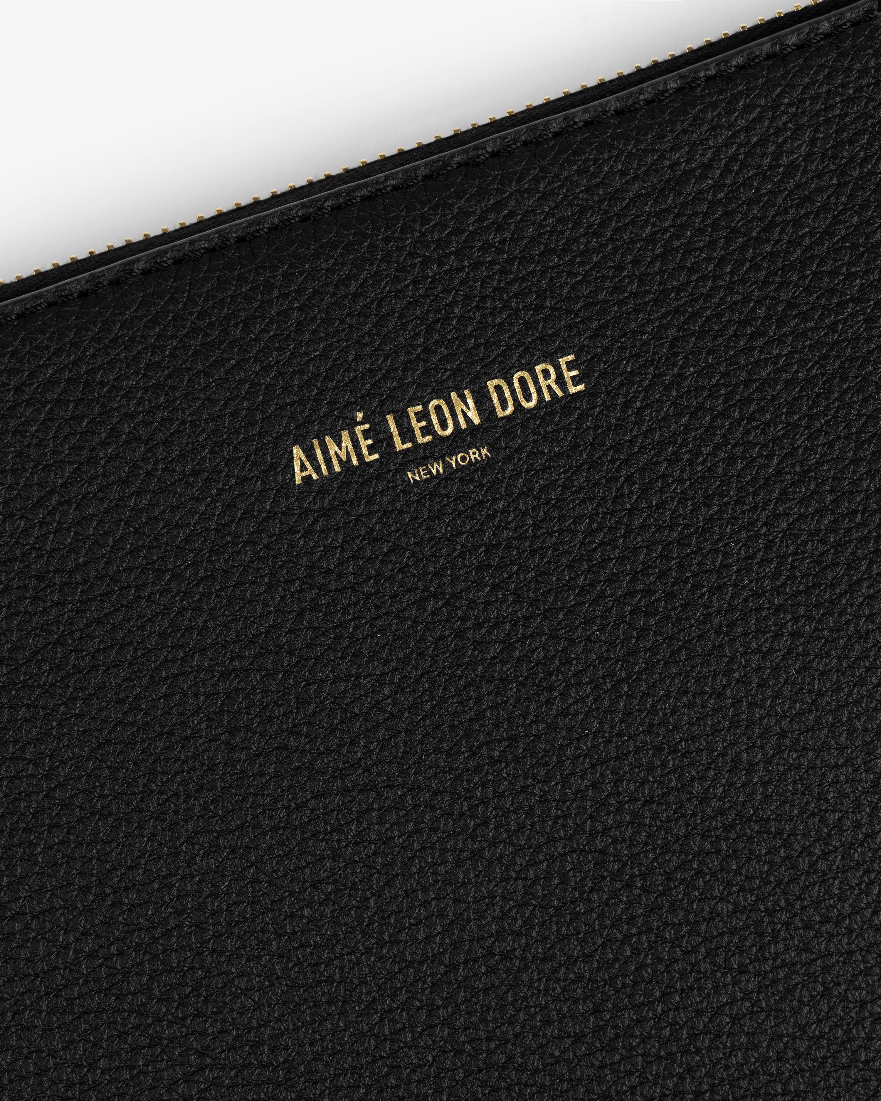 Close-up of a black textured Large Leather Pouch with AIMÉ LEON DORE NEW YORK embossed in gold letters.