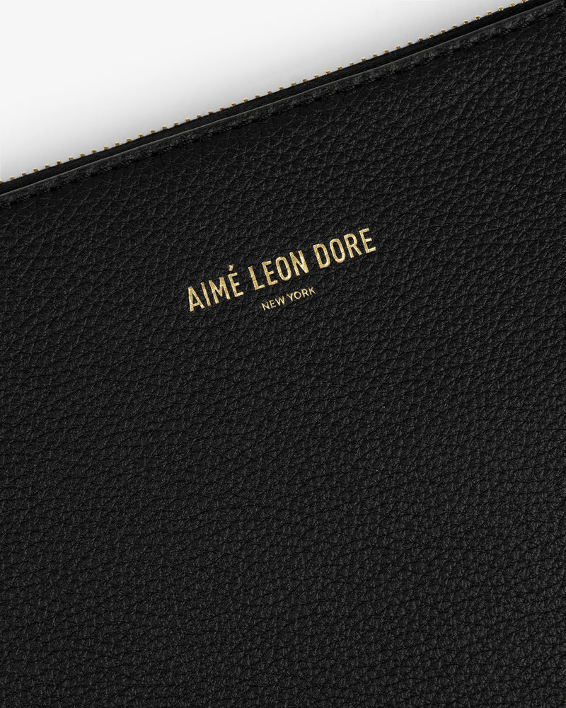 Close-up of a black textured Large Leather Pouch with AIMÉ LEON DORE NEW YORK embossed in gold letters.