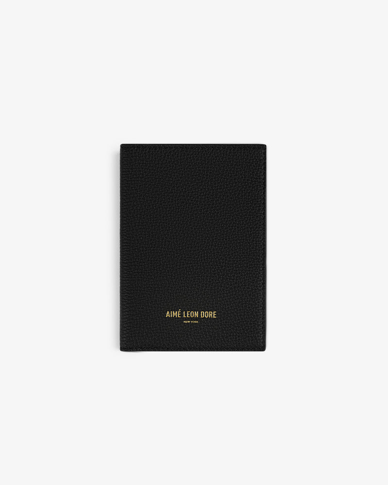 A black Leather Passport Holder with AIMÉ LEON DORE in gold at the bottom center.