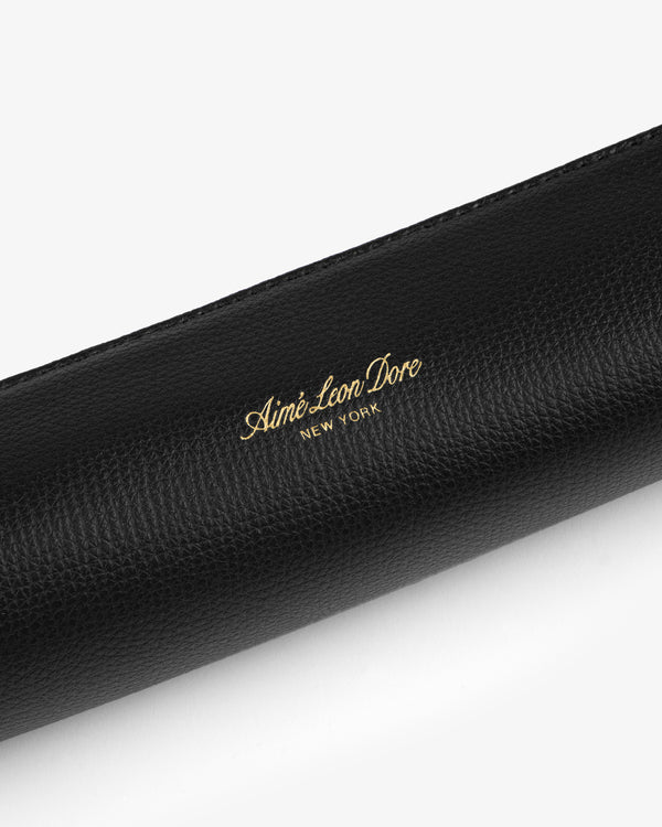 Black textured leather pencil case with gold Aimé Leon Dore New York logo embossed at the center.