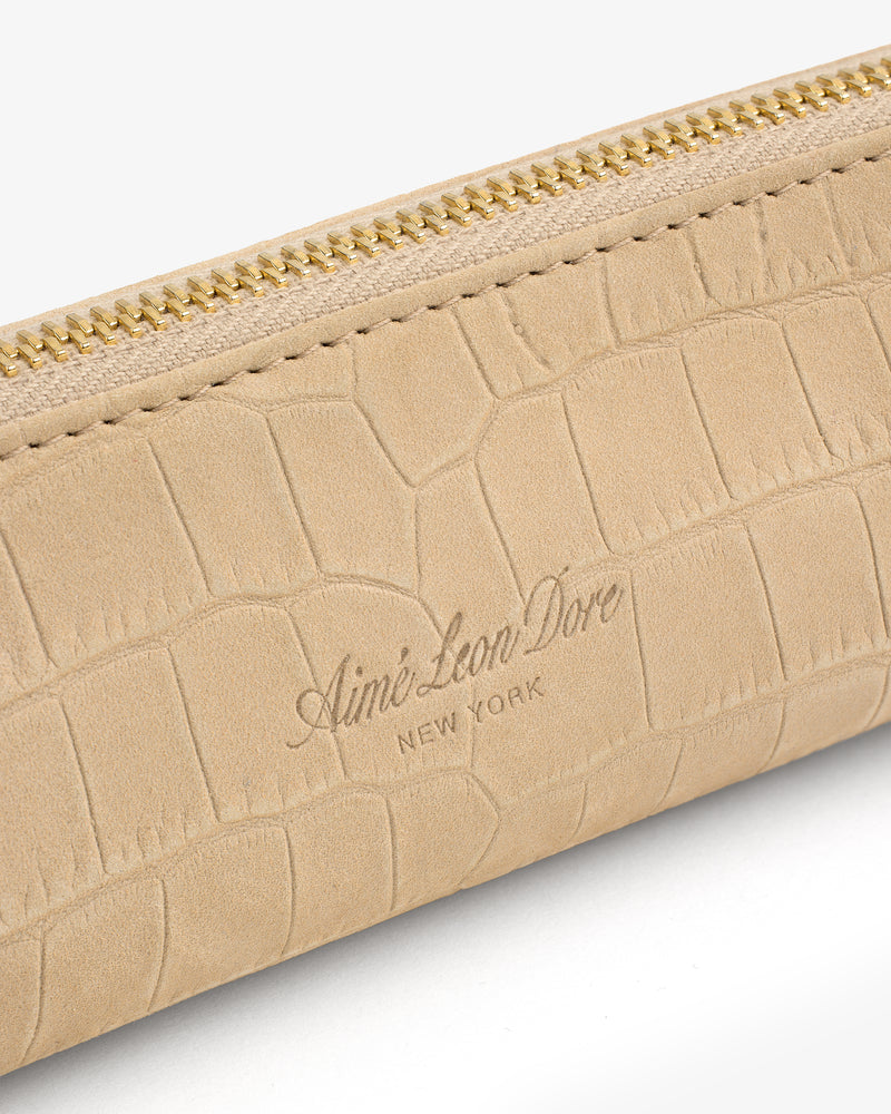 Close-up of the Croc-Embossed Nubuck Pencil Case with gold zipper and Aimé Leon Dore New York embossed on beige leather.