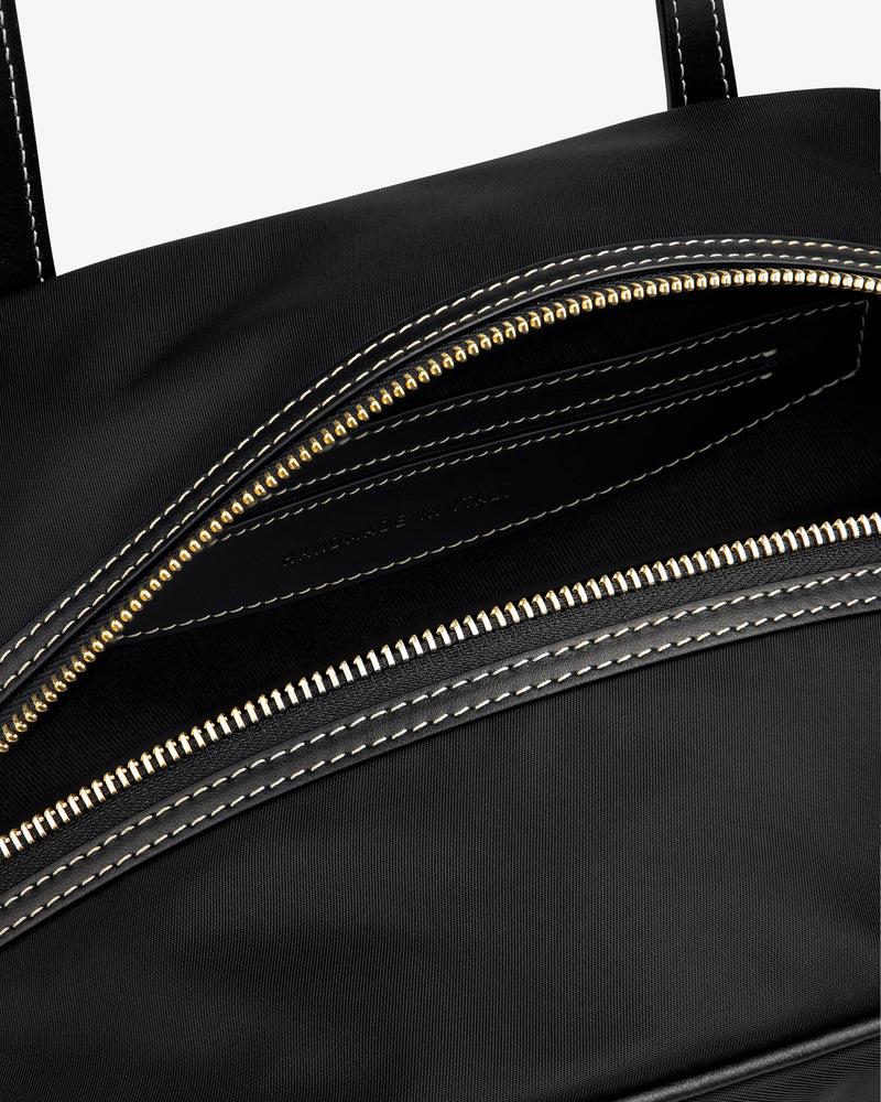 Close-up of the Mini Duffle Shoulder Bag in black with a gold zipper and white stitching, partially open to reveal interior.