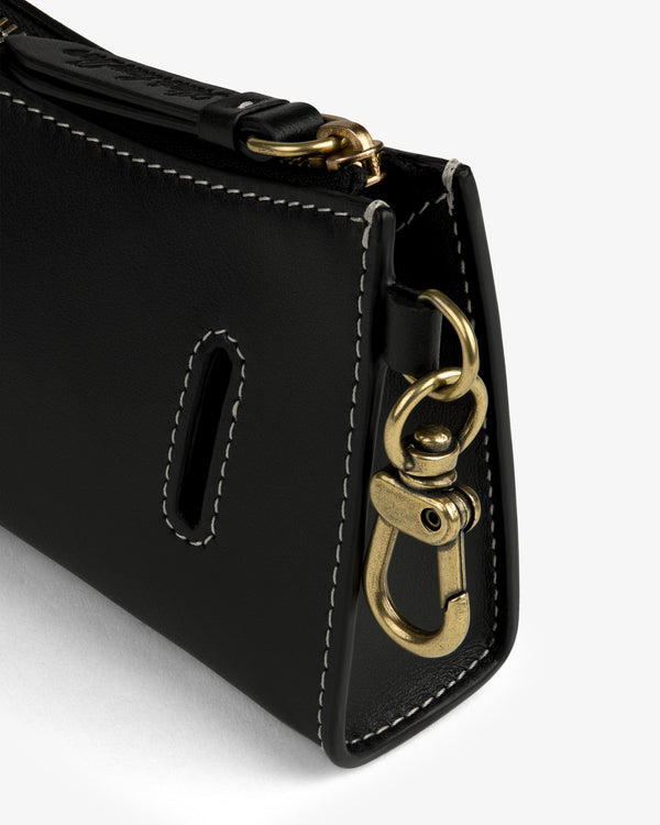 Close-up of the Convertible Leather Belt Bag's black leather corner with white stitching and a gold swivel clasp.