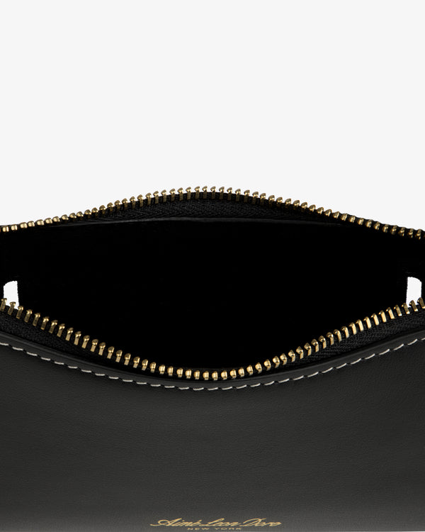 Close-up of the Convertible Leather Belt Bag: open black leather pouch with gold zipper, white stitching, and empty interior.
