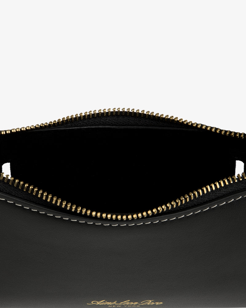 Close-up of the Convertible Leather Belt Bag: open black leather pouch with gold zipper, white stitching, and empty interior.