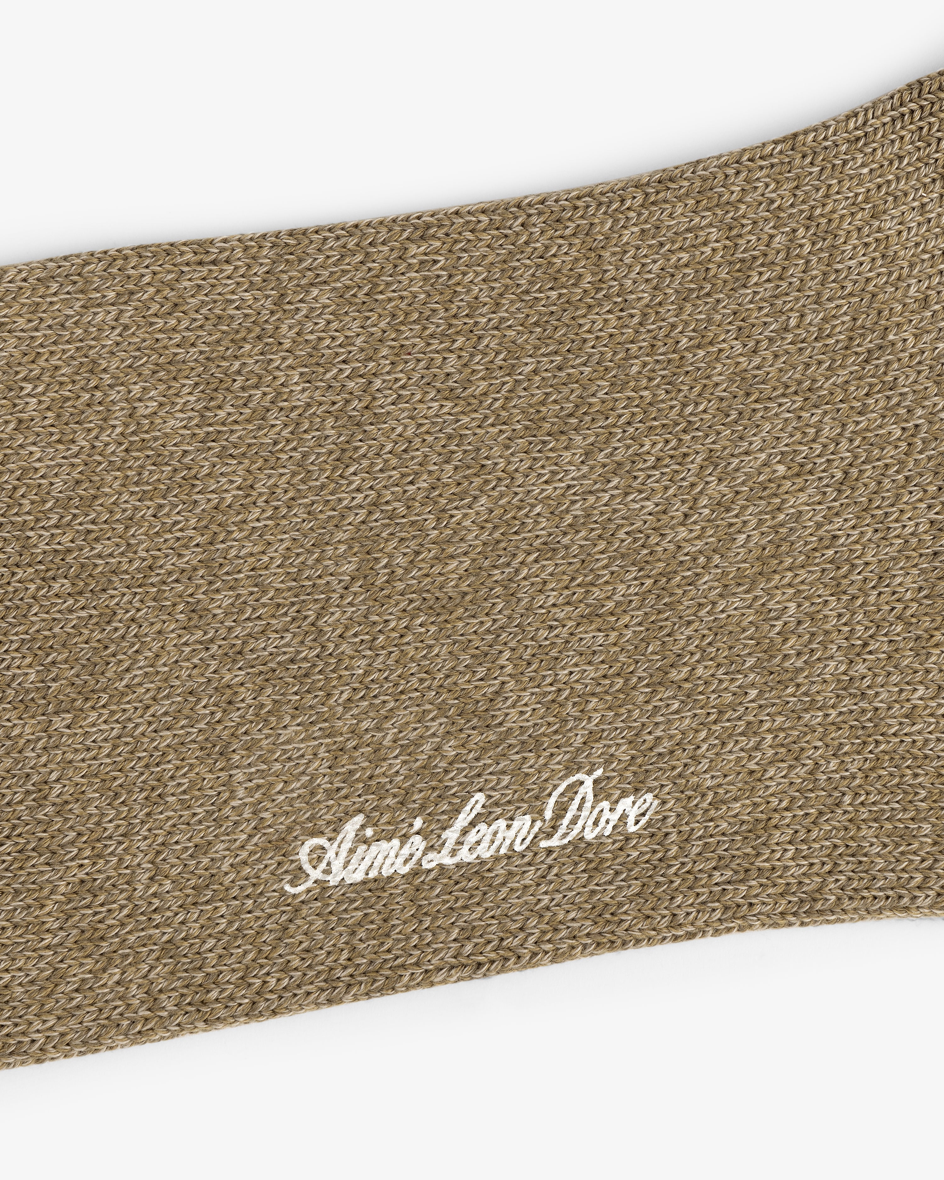 Close-up of brown knit Marled Quarter Sock with Aimé Leon Dore embroidered in white cursive.