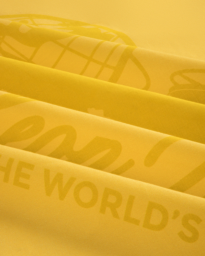 Close-up of the Sun Faded Unisphere Bandana's yellow fabric with layered printed text and graphics.