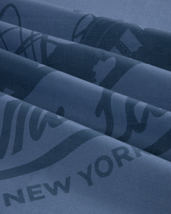 Close-up of folded Sun Faded Unisphere Bandana in blue with partial printed text, including “NEW YORK.”.