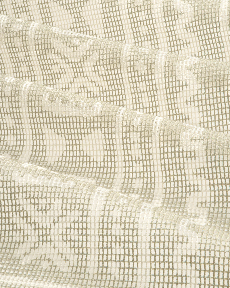 Close-up of the Mesh Tapestry Bandana in cream, showing its textured grid and floral pattern, softly folded.