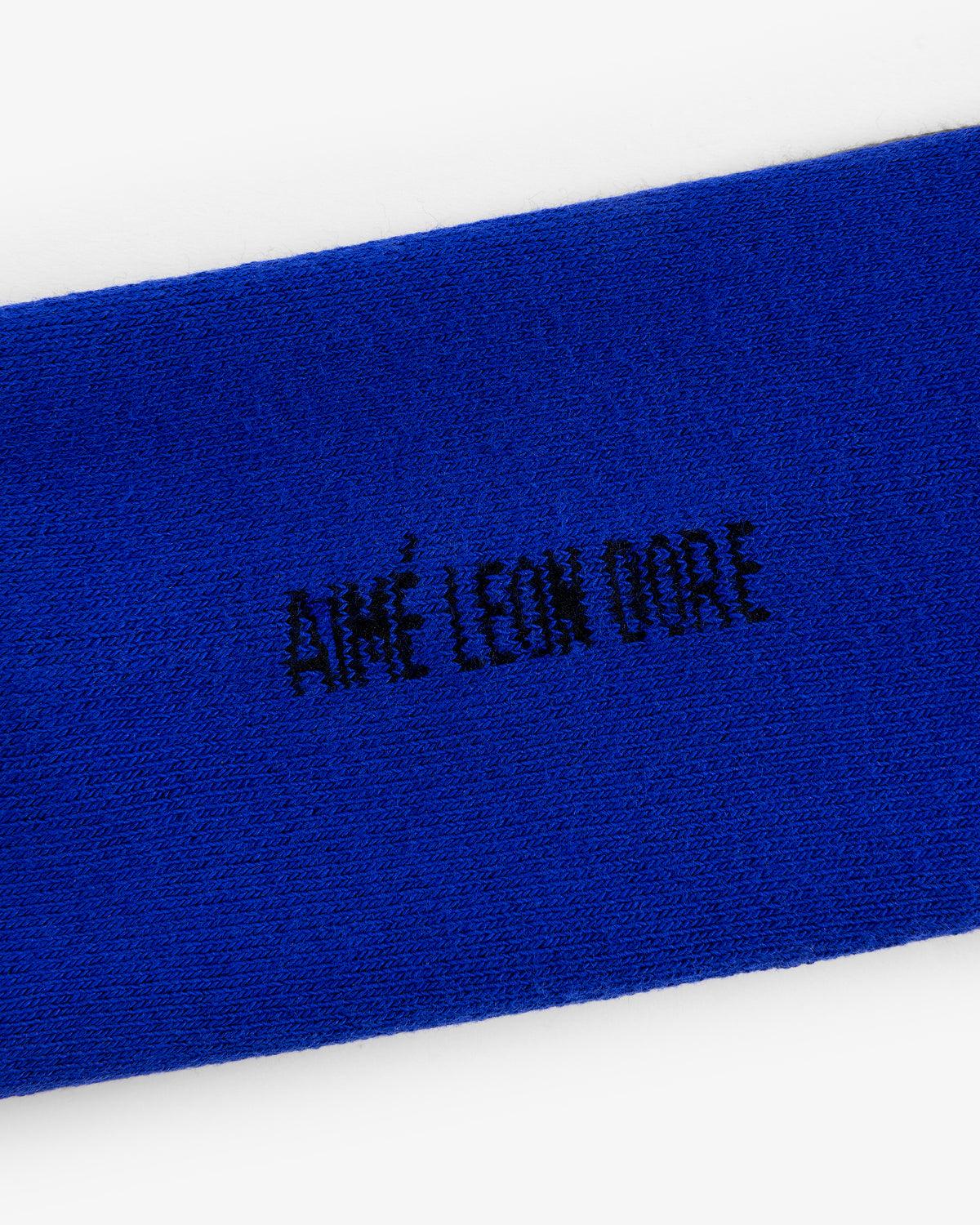 Close-up of blue Crew Sock 3-Pack with AIMÉ LEON DORE embroidered in black, all-capital letters.