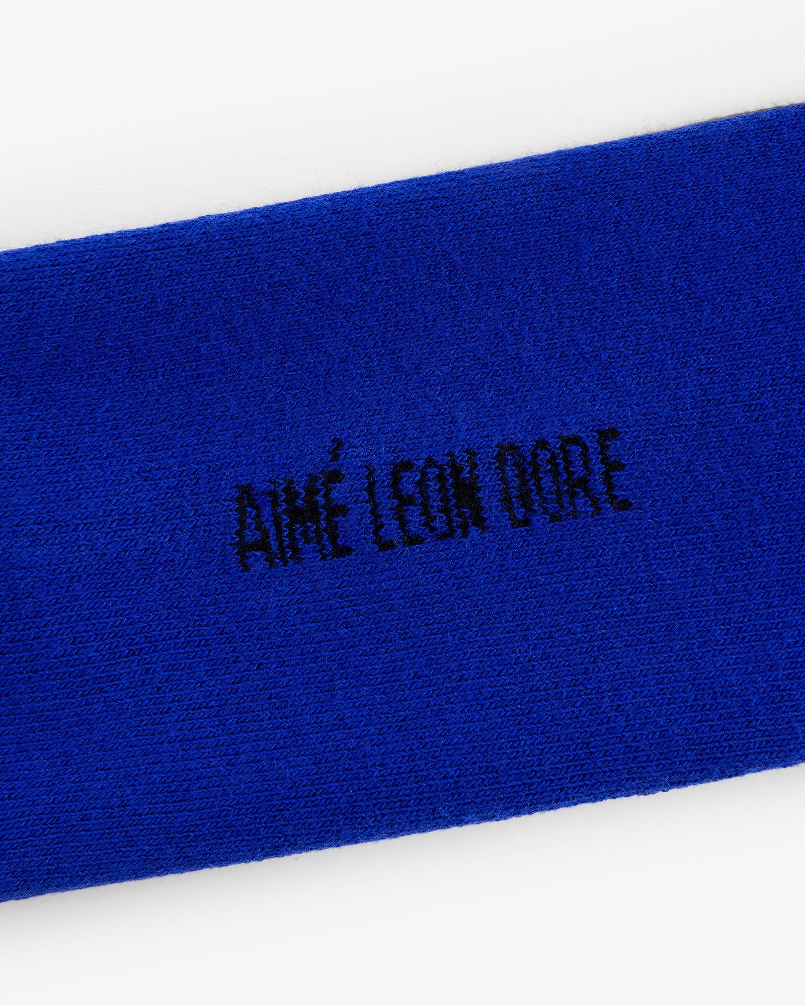 Close-up of blue Crew Sock 3-Pack with AIMÉ LEON DORE embroidered in black, all-capital letters.