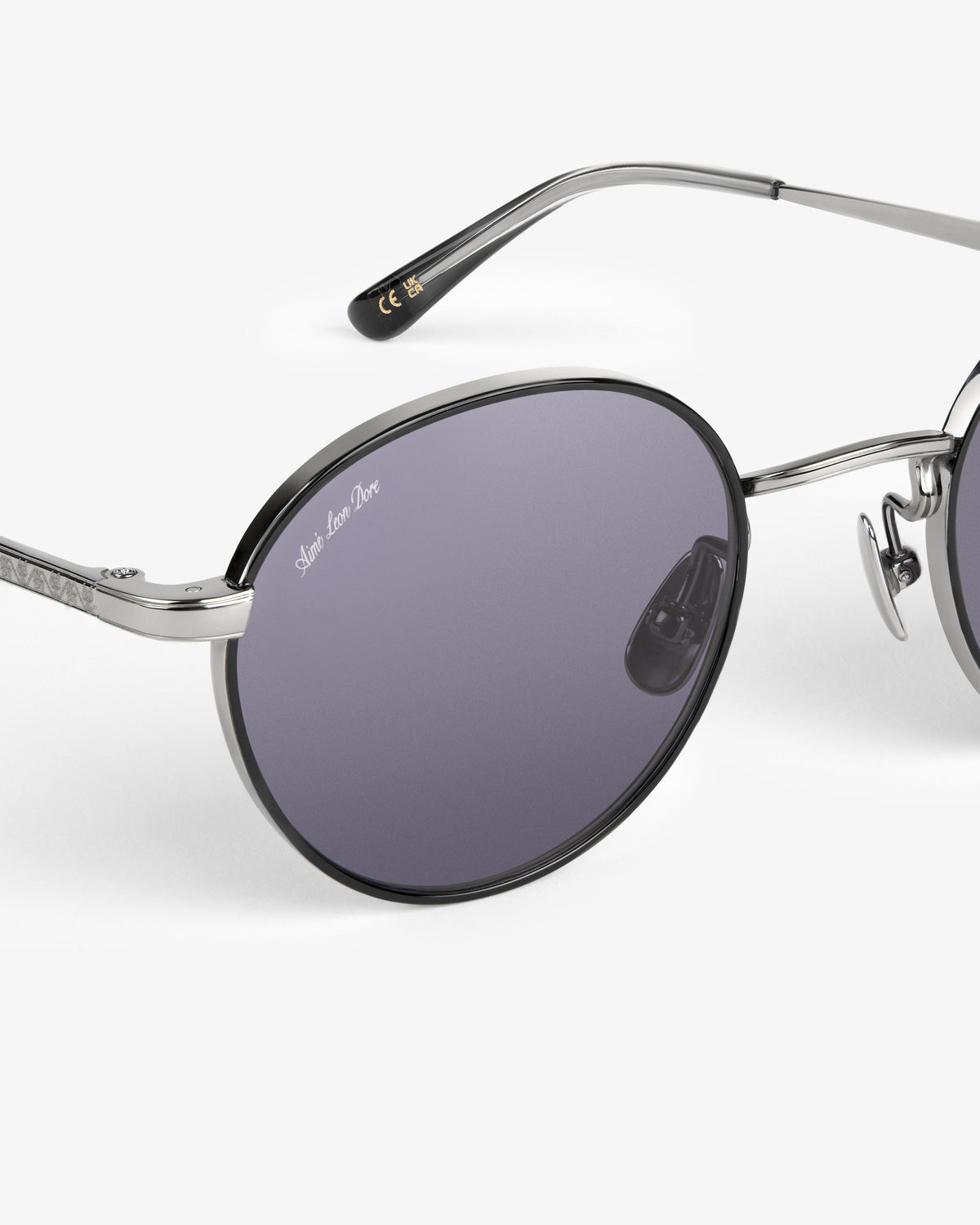 Close-up of Giórgios Sunglasses with round dark lenses and silver metal frames on a white background.