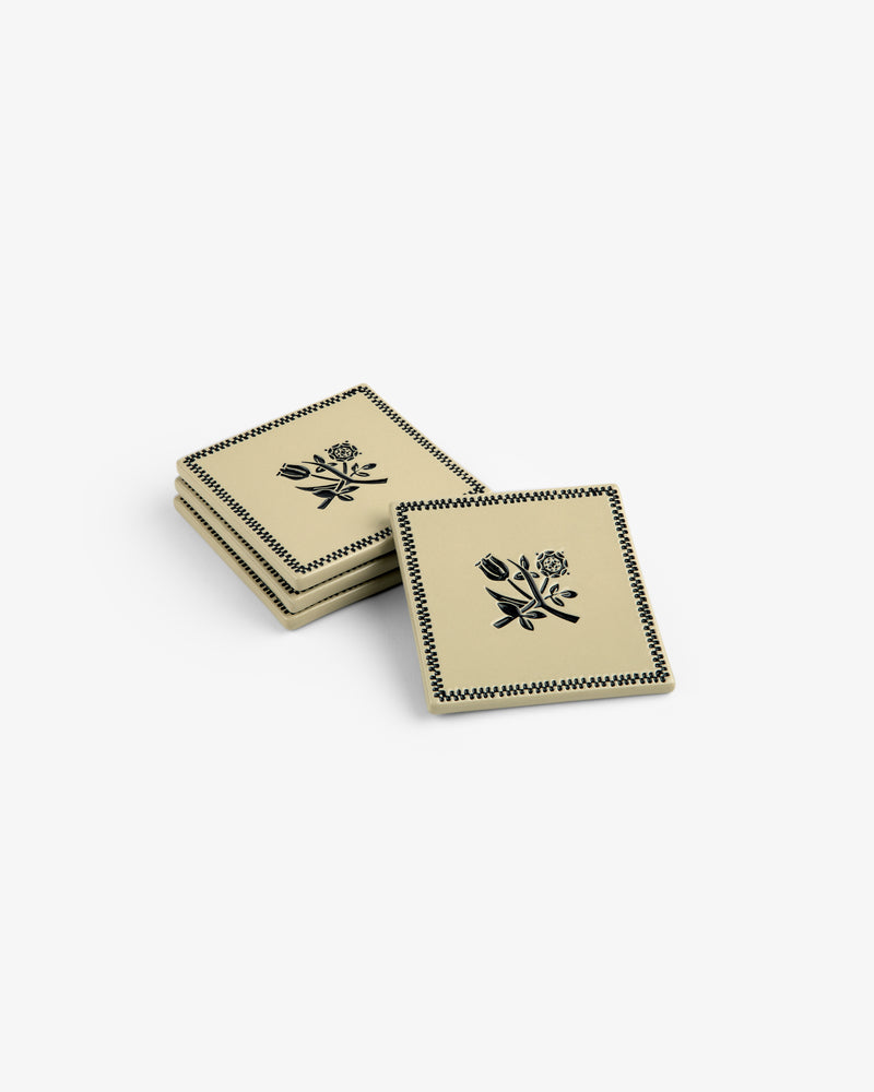 Set of 4 Crest Coasters: beige squares with black floral designs and patterned borders, stacked on a white background.