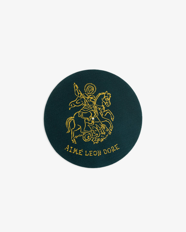 Round green Graphic Slip Mat featuring a gold knight on horseback and AIMÉ LEON DORE text below.