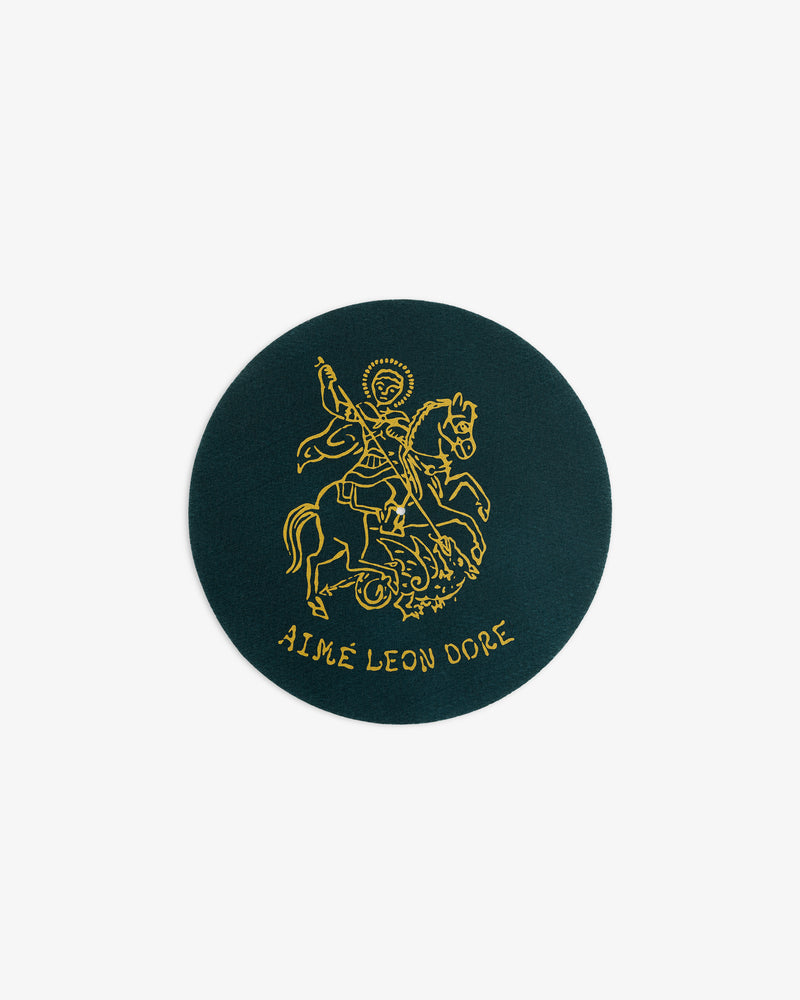 Round green Graphic Slip Mat featuring a gold knight on horseback and AIMÉ LEON DORE text below.