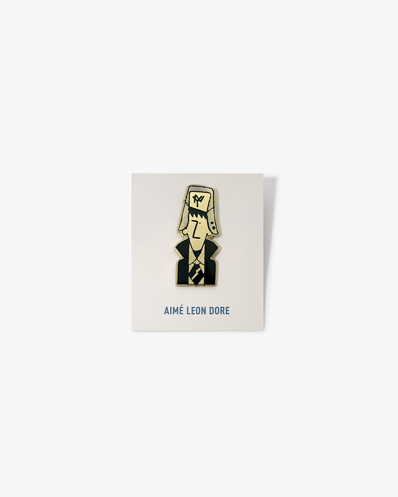 Graphic Pin featuring a cartoon person in a suit and hat, displayed on AIMÉ LEON DORE branded card.