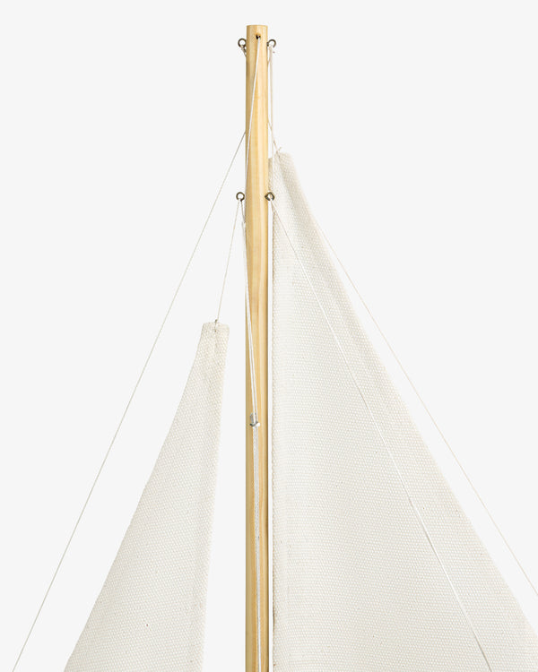Close-up of the Walnut Model Sailboat’s mast and white sails set against a plain white background.