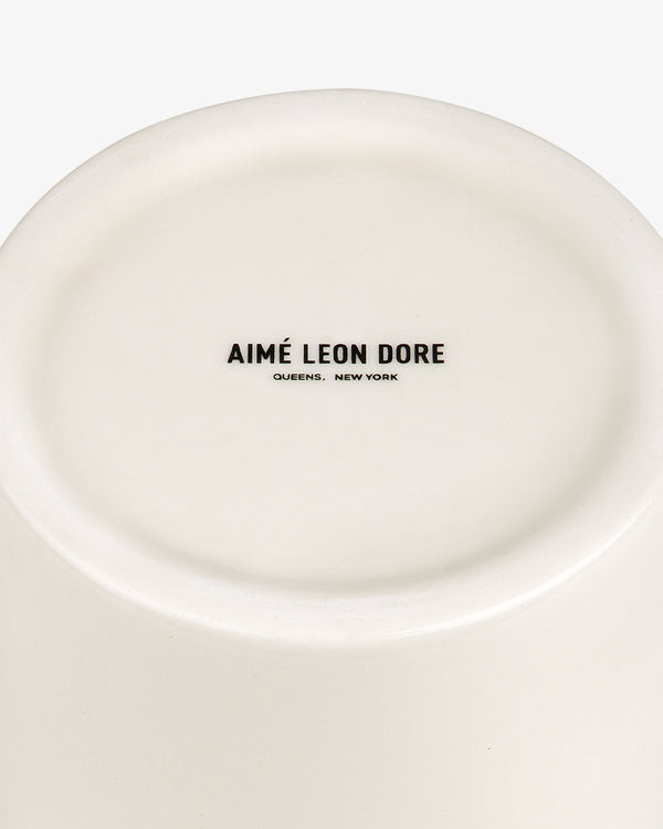 Bottom of a Krylon Ceramic Spray Can Vessel with AIMÉ LEON DORE QUEENS, NEW YORK printed in black text.