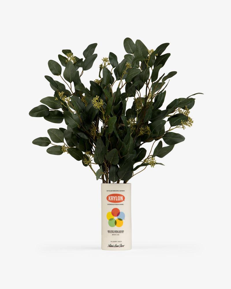 A leafy green plant sits in a Krylon Ceramic Spray Can Vessel, used as a vase, against a white background.