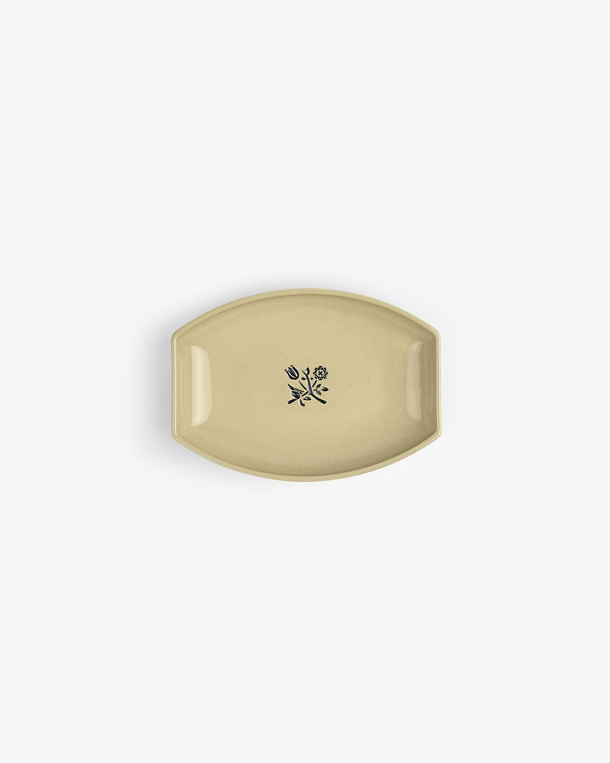 The Crest Catchall: a small beige ceramic dish with a black floral design at its center, shown from above.