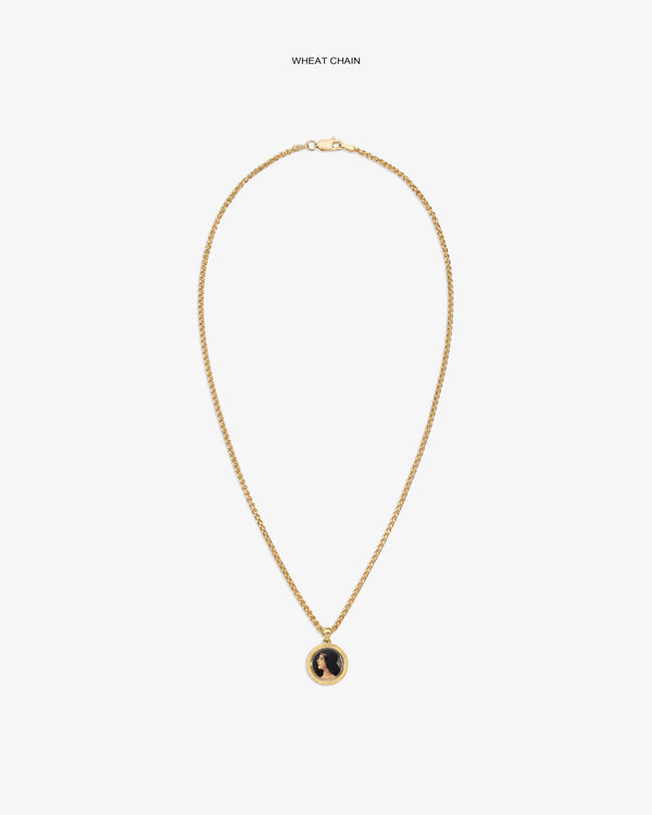 14Kt Gold Hera Pendant on a wheat chain with a black and gold round pendant, shown on a plain white background.