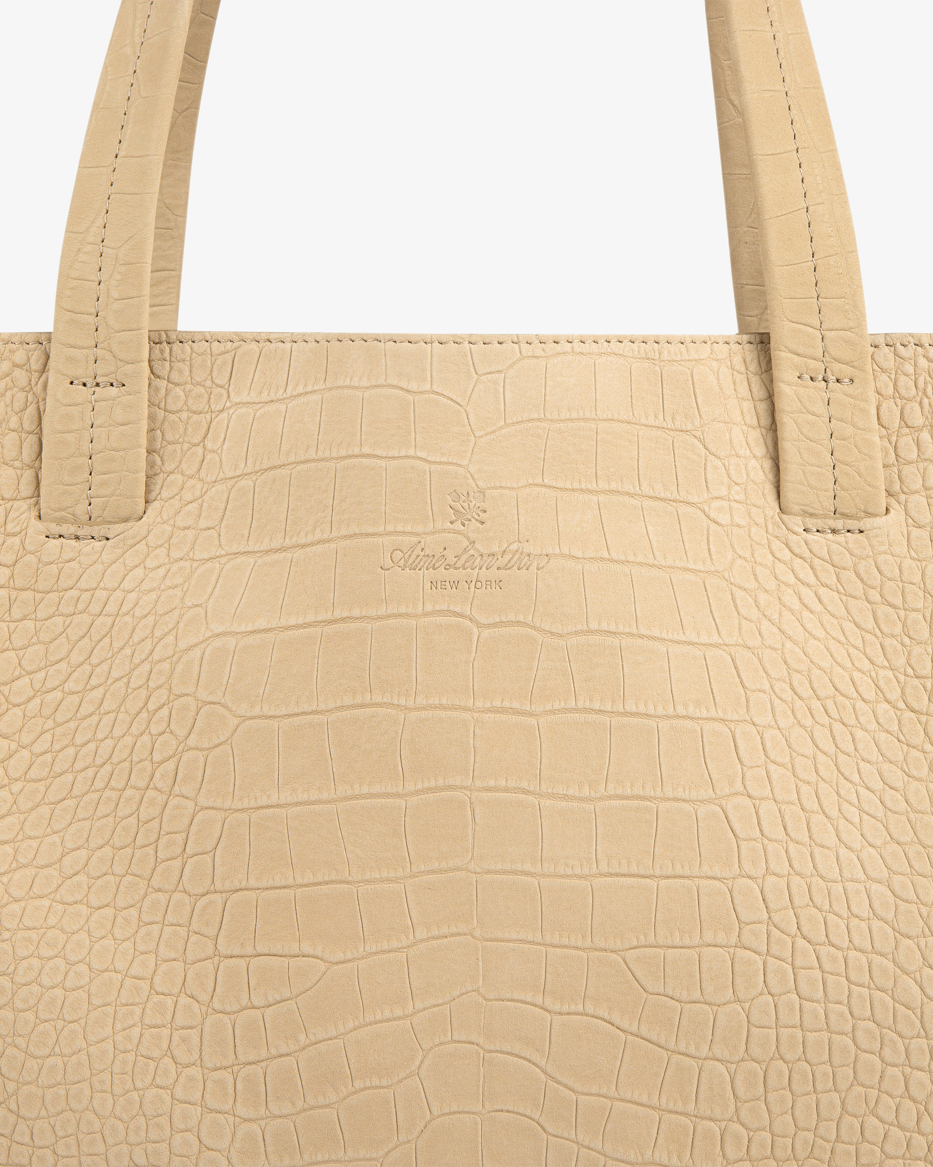 Close-up of the Croc-Embossed Nubuck Tote Bag in beige with two handles and subtle center branding.