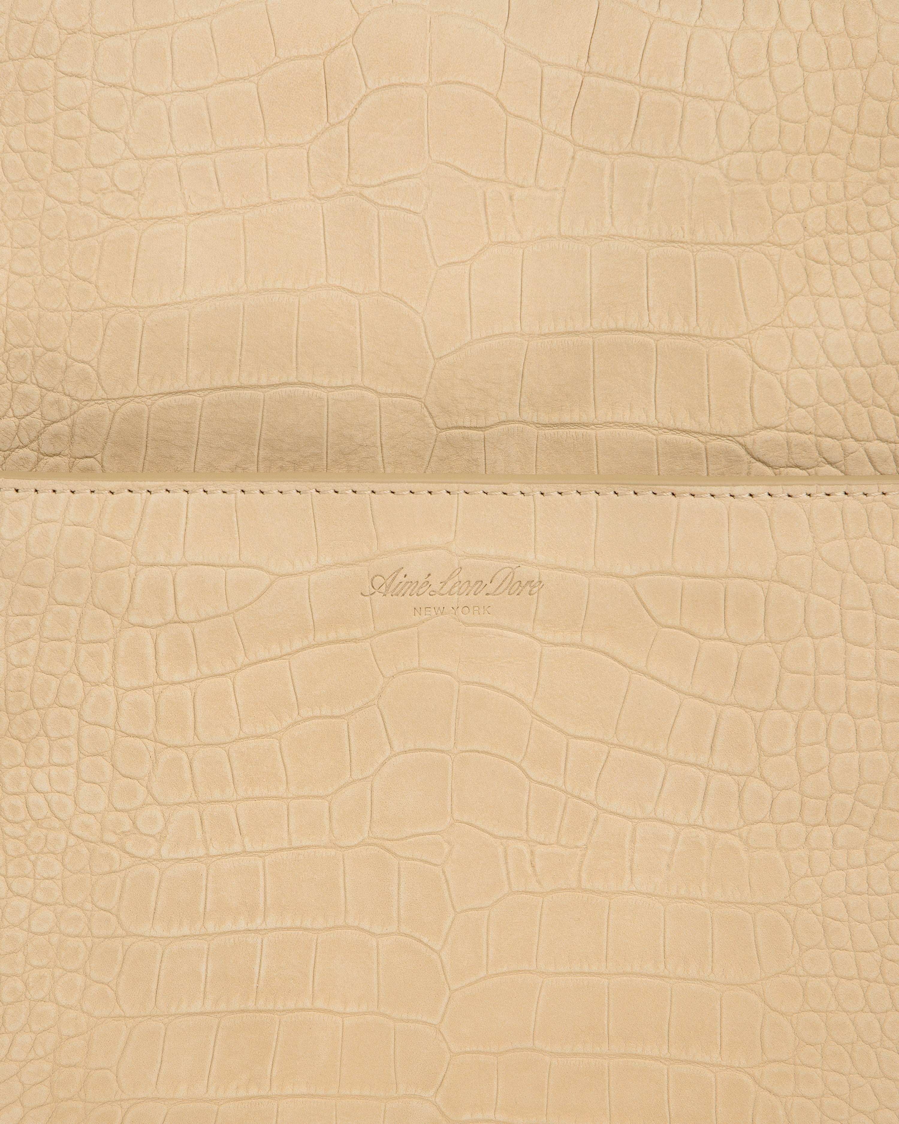 Close-up of beige Croc-Embossed Nubuck Duffle with Aime Leon Dore New York logo debossed at the center.