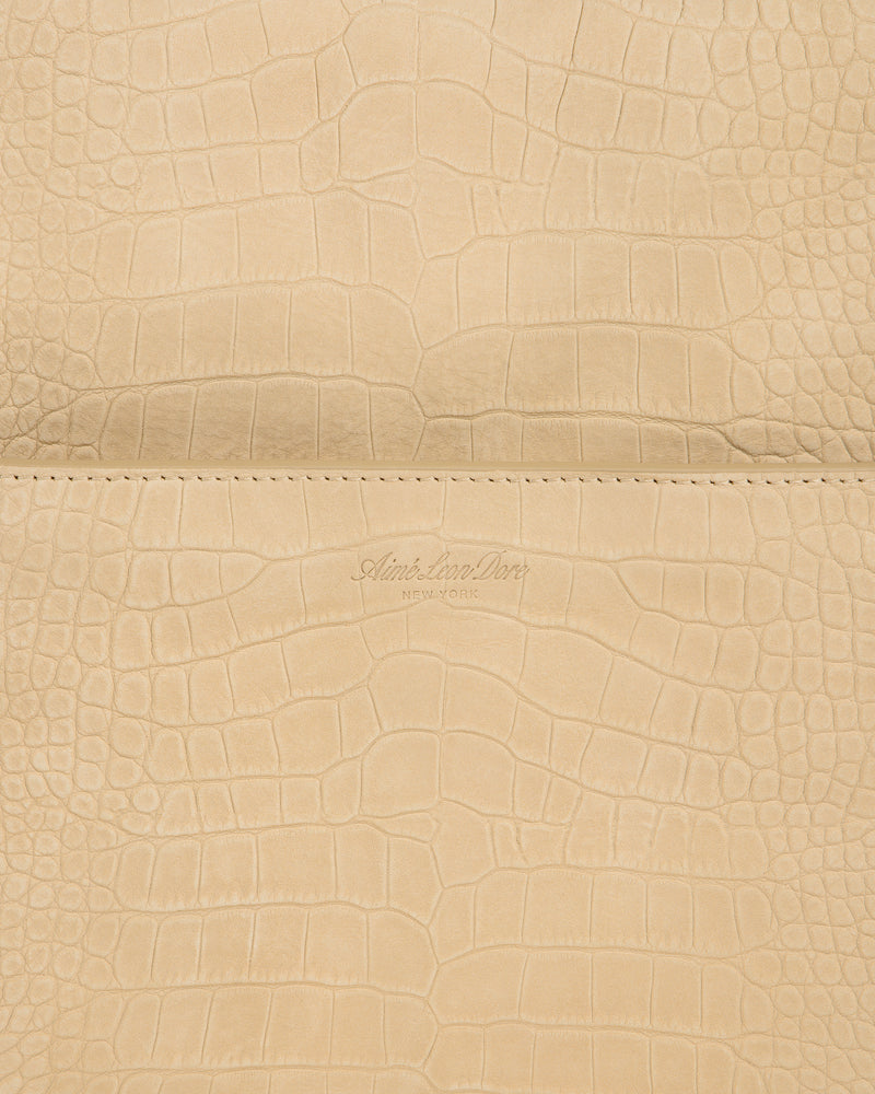 Close-up of beige Croc-Embossed Nubuck Duffle with Aime Leon Dore New York logo debossed at the center.
