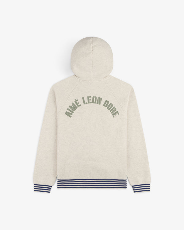 Dock Hoodie: Beige with AIMÉ LEON DORE green text on back, blue-striped cuffs and hem.