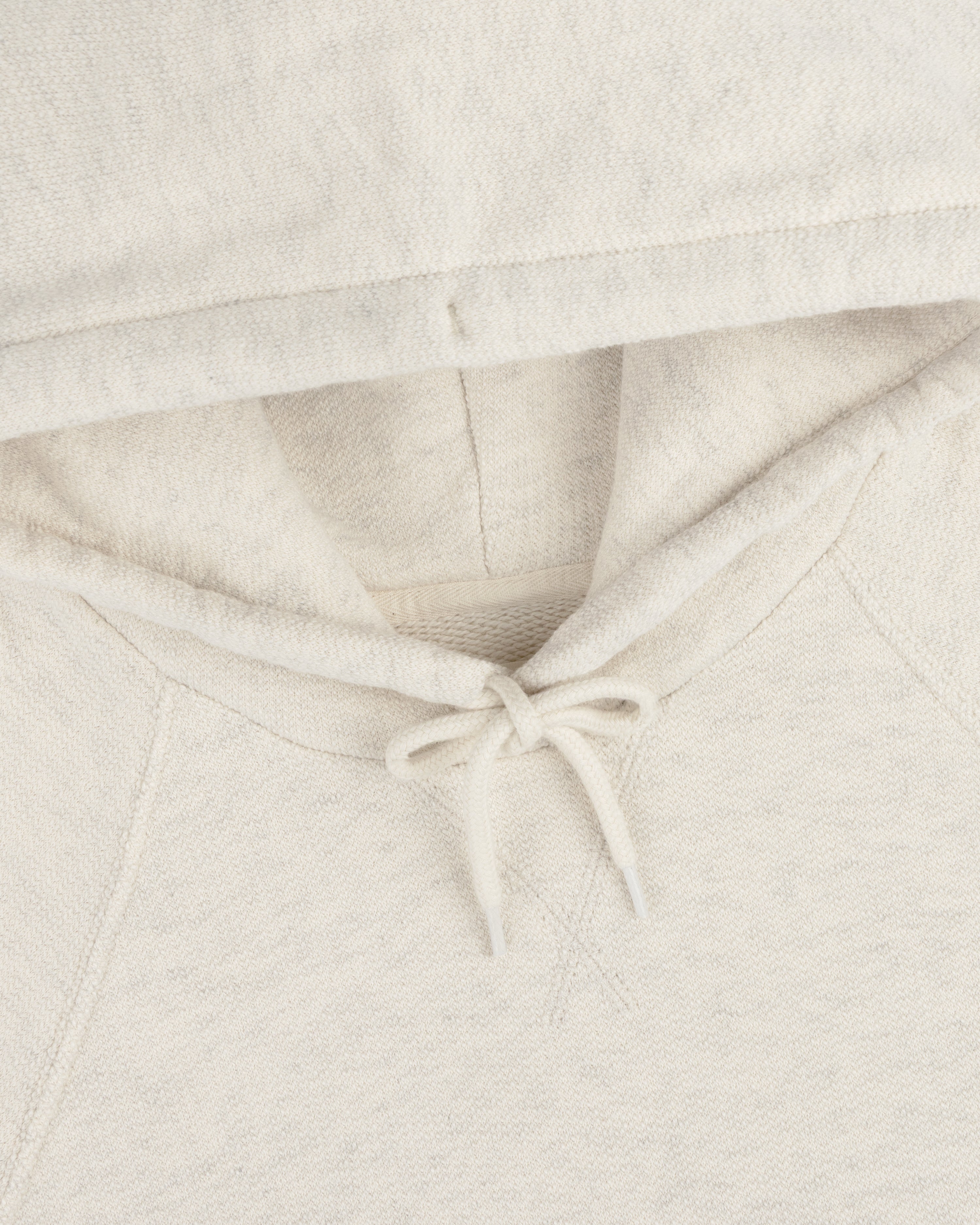 Close-up of the Dock Hoodie in cream, highlighting the hood, drawstrings, and neckline.