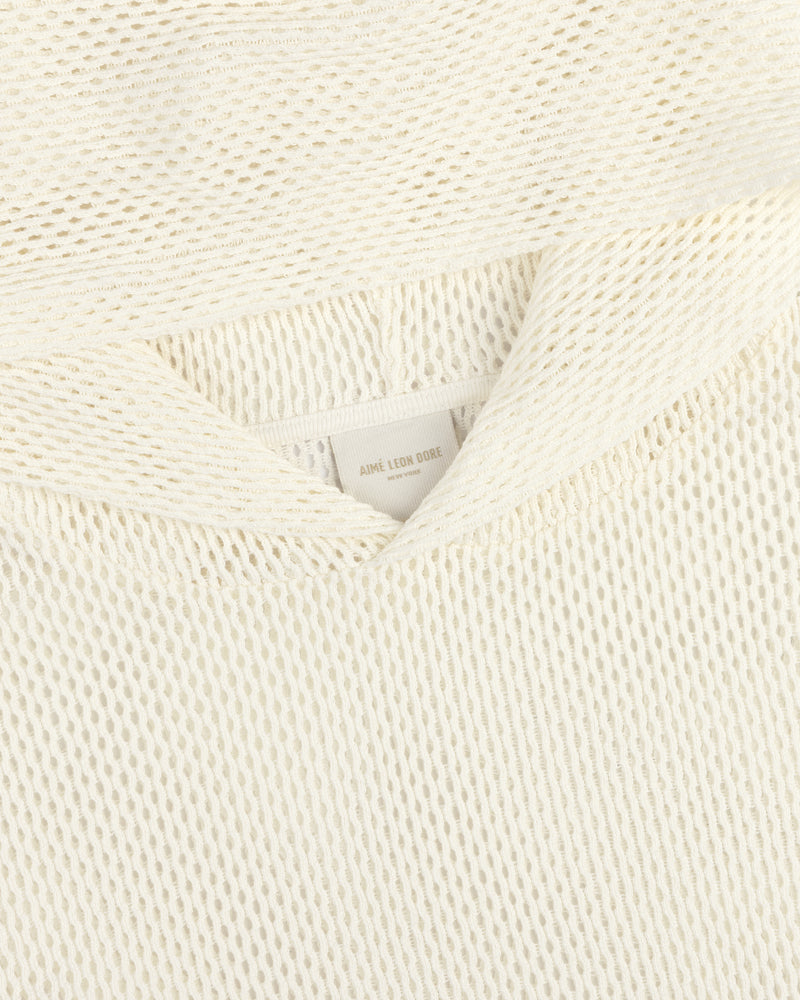 Close-up of an off-white Open Mesh Hoodie with textured knit fabric and a visible neck label reading Aime Leon Dore.