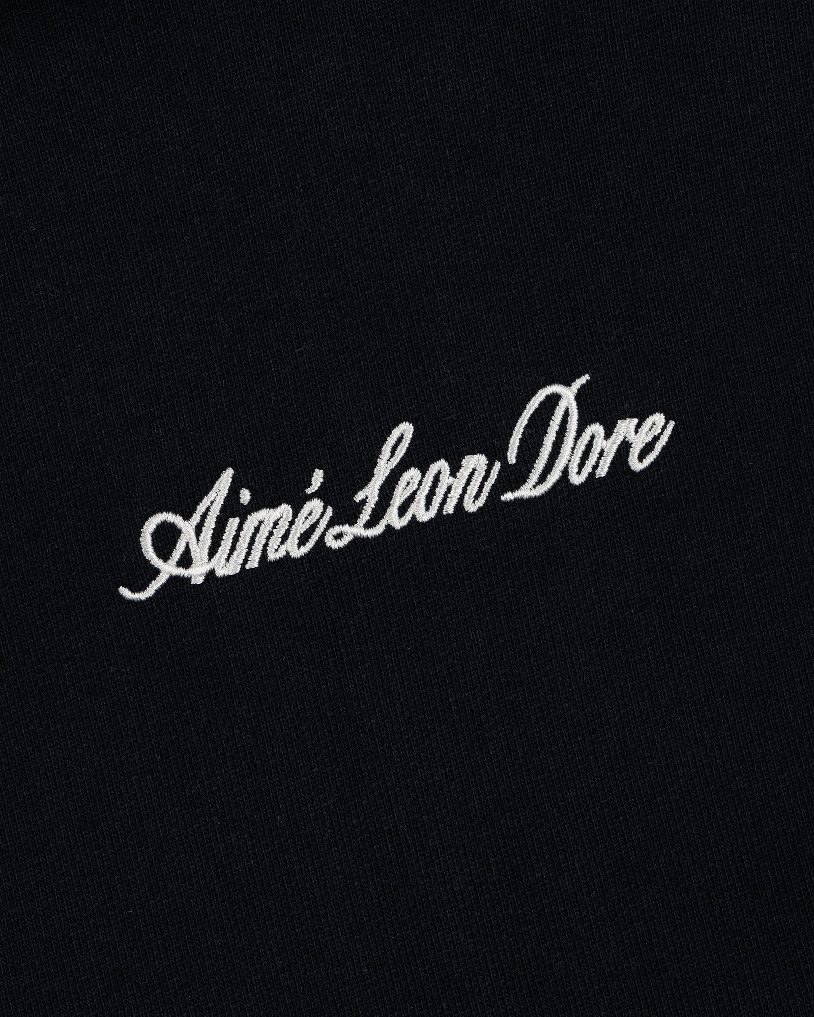 Embroidered Logo Hoodie in black with "Aimé Leon Dore" in white cursive across the center.